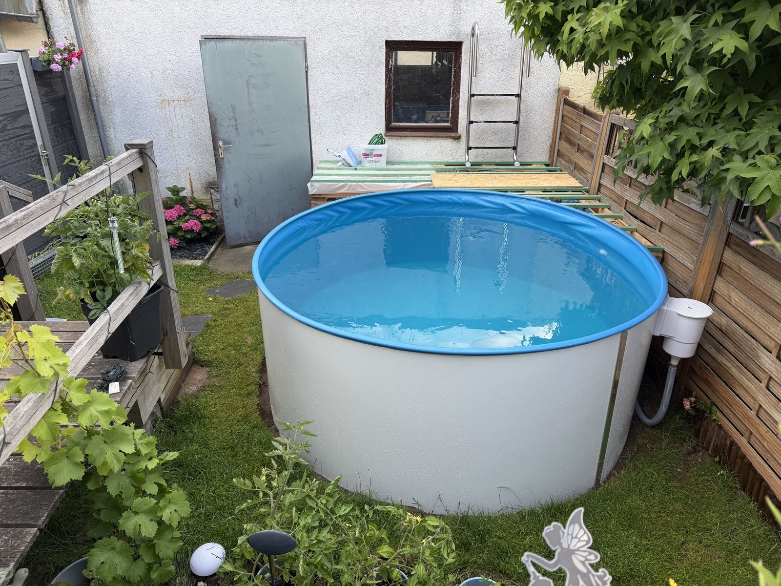 Gefülltes Poolbecken, dahinter die Unterkonstruktion für das Podest