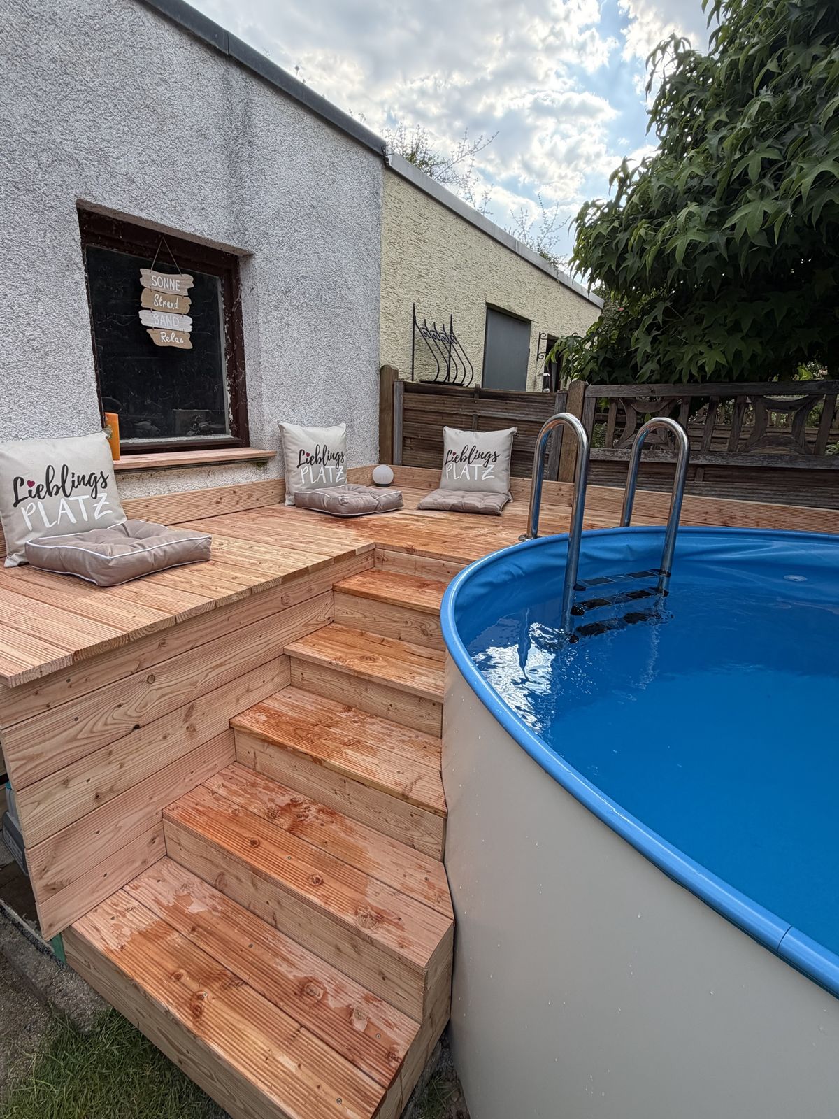 Holztreppe aus Lärchendielen, die am Becken entlang zum Podest führt