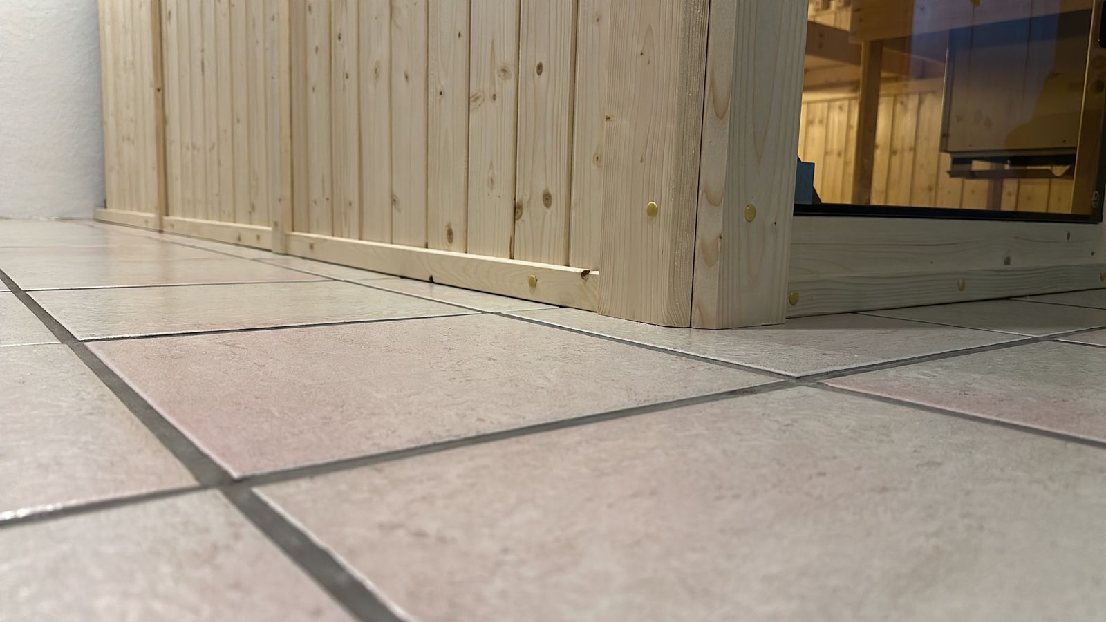 Nahaufnahme: Holzverkleidung schließt sauber an den Fliesenboden an